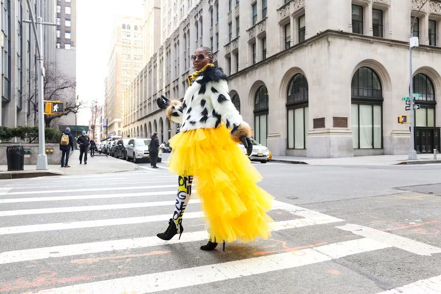 A woman in a yellow tulle skirt crossing a city street