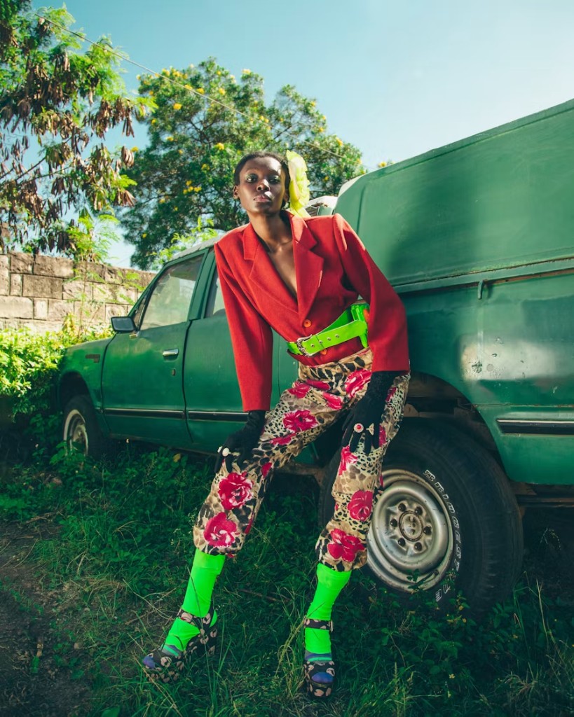 A woman in a red blazer sitting on the back of a green truck