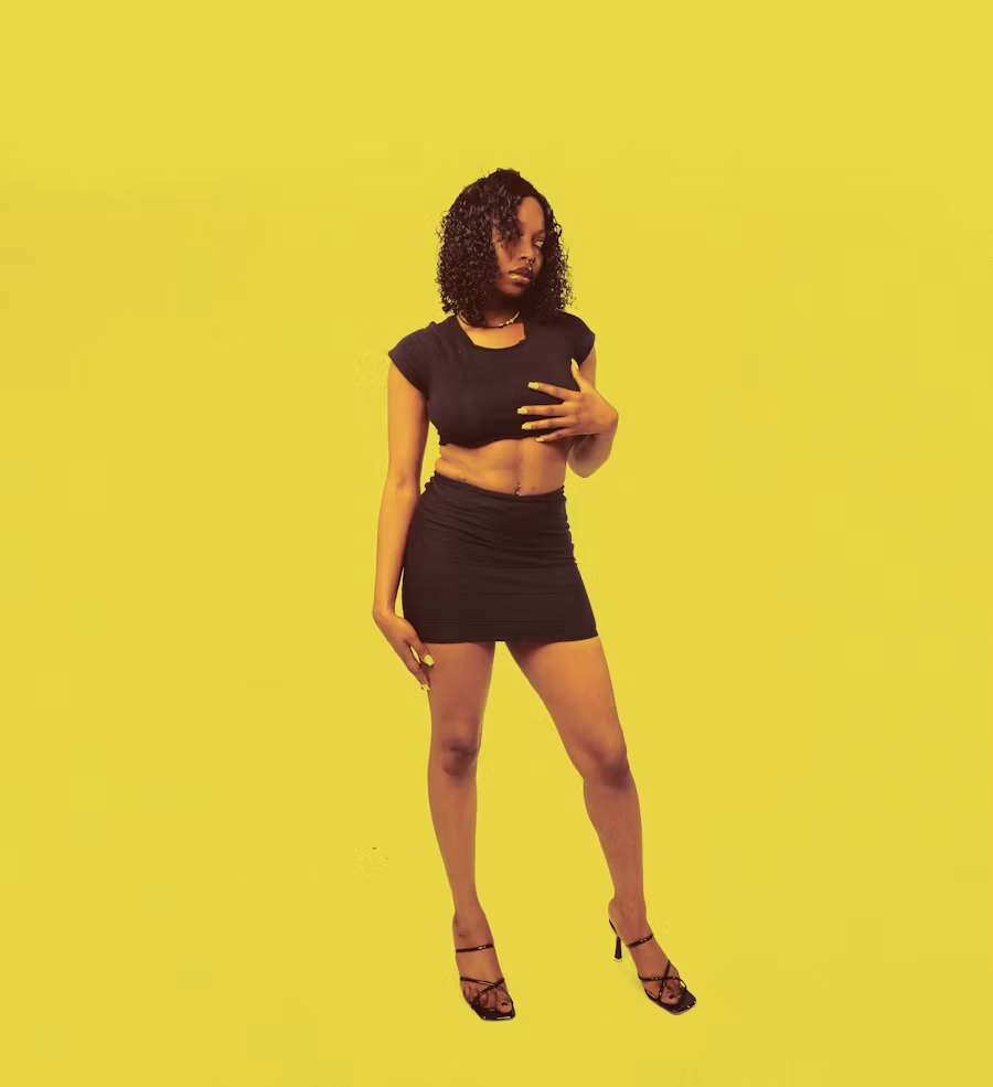 A woman in a black top and skirt against a yellow background